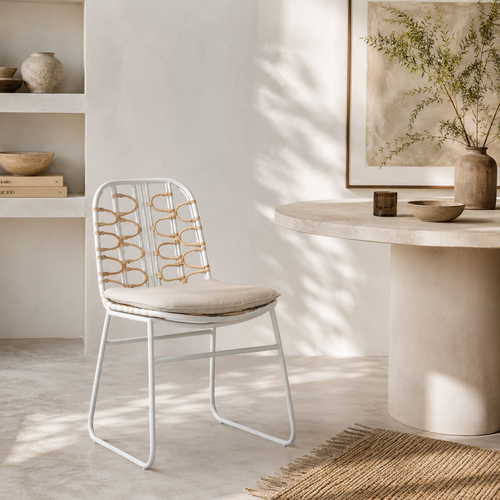 Modern chair with decorative backrest in a bright room with a table and decor items.
